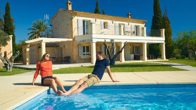 young couple enjoying first warm days of spanish spring at swimming pool of their finca house.