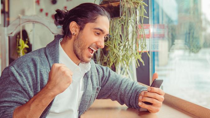 Excited man checking news on smart phone stock photo