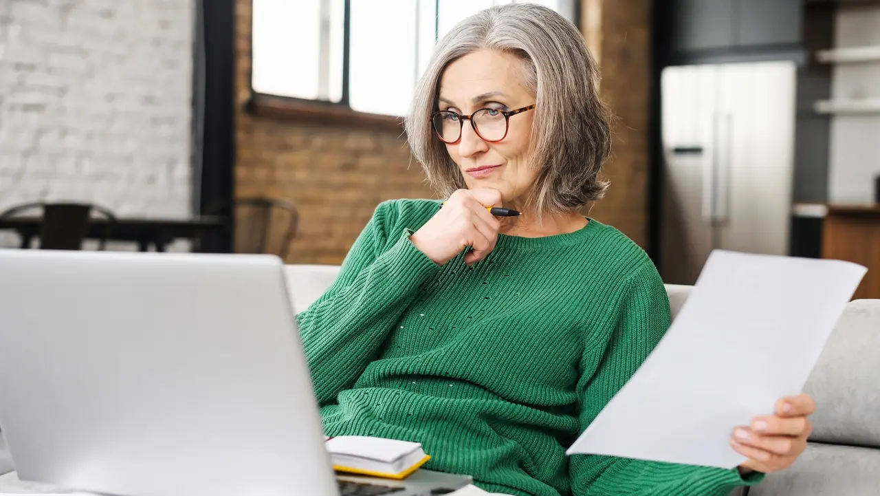 A Serious Accountant Sitting On The Living Room Looking At The Stock Photo Of The Laptop