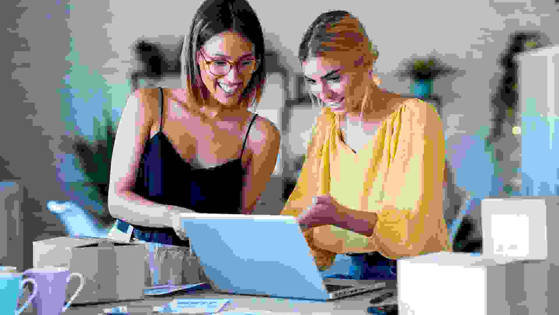 Two beautiful freelance business women seller checking product order with computer in their startup small business. stock photo