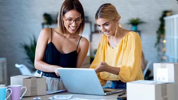 Two beautiful freelance business women seller checking product order with computer in their startup small business. stock photo