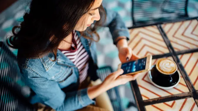 A millennial looks at her phone and makes financial plans.