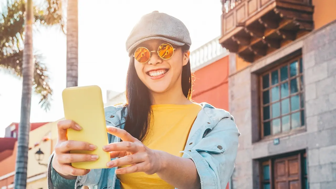 Happy Asian girl using mobile smartphone outdoor - Chinese social influencer having fun making video story for new trends social networks app - People, millennial generation and technology concept stock photo