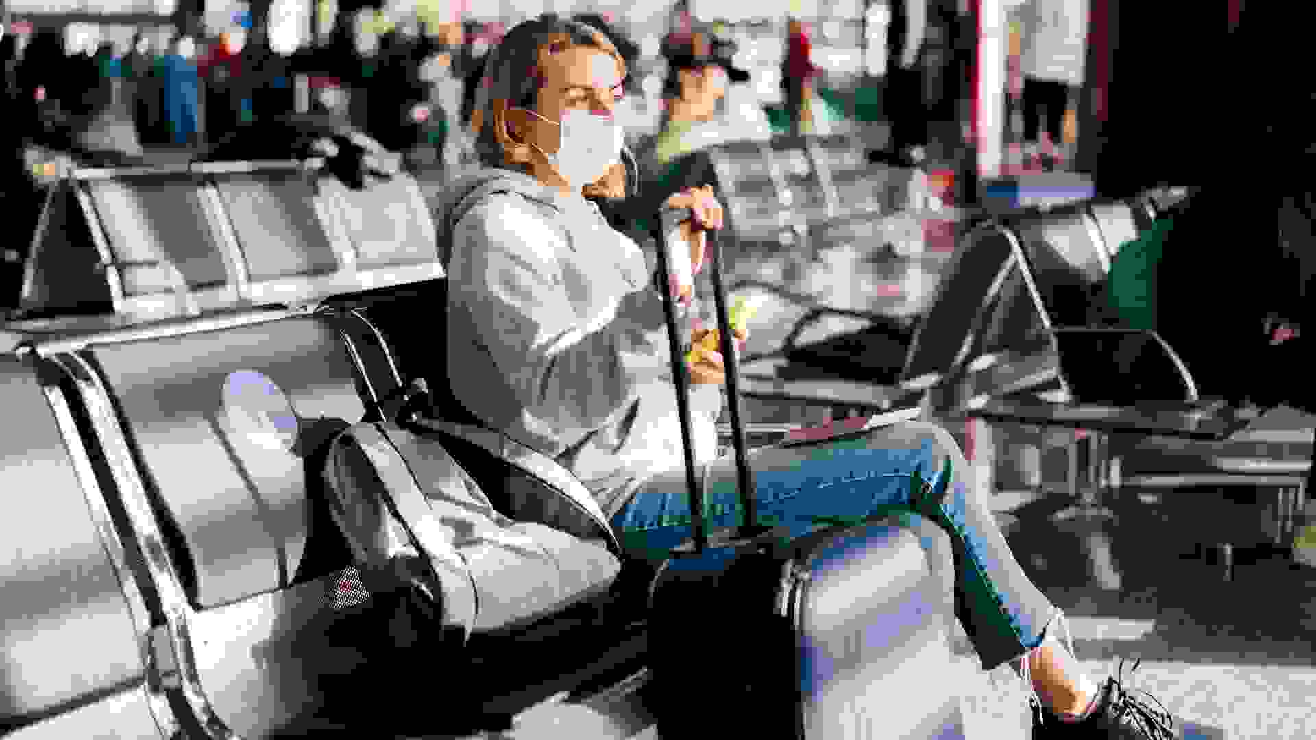 A female passenger in a medical mask is waiting for a flight at the airport. stock photo