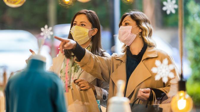 Two Young Women holding shopping bags and wearing face mask because of Covid-19.
