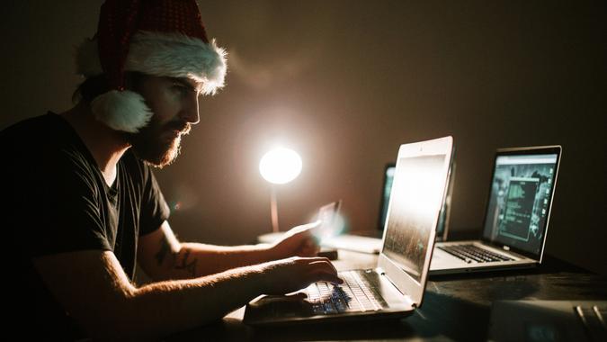 Hacker thief with santa hat stealing information from a credit card.