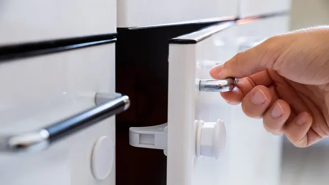 Close-up Photo Of Man Opening Child Proof Kitchen Cabinets.