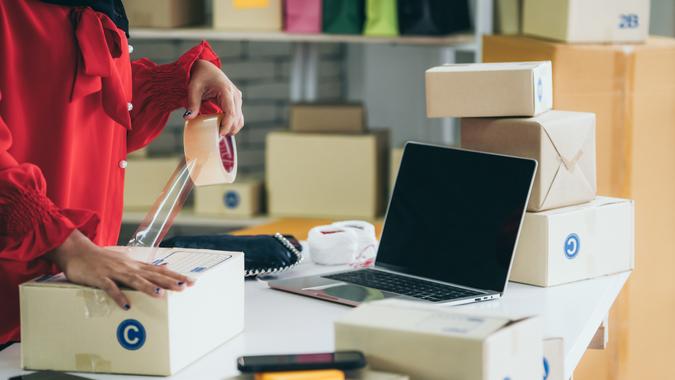 Online seller works at home office and packs shipping delivery box to customer.