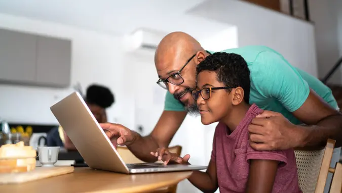 Father encouraging son on homeschooling or doing a video call/watching a movie.