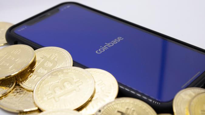 Bitcoins placed next to the Coinbase app on iPhone, illustrating one of the largest providers of Bitcoin, pictured in Cologne, Germany on April 14, 2021.