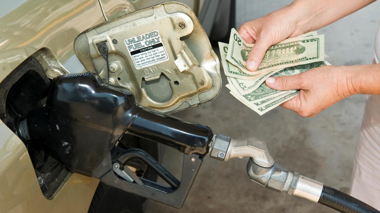 Horizontal shot of someone's hands holding money at the gas pump.