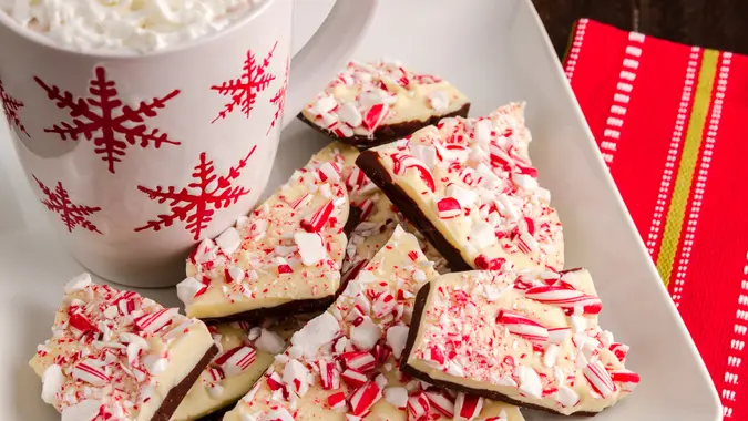 Plate of holiday chocolate peppermint bark with cup of hot cocoa with whipped cream.