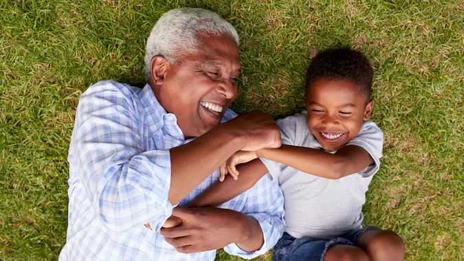 Grandfather and grandson play lying on grass, aerial view.