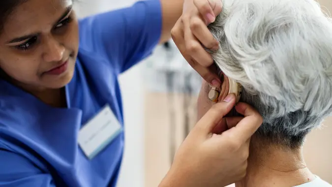 An elderly woman with hearing aid.