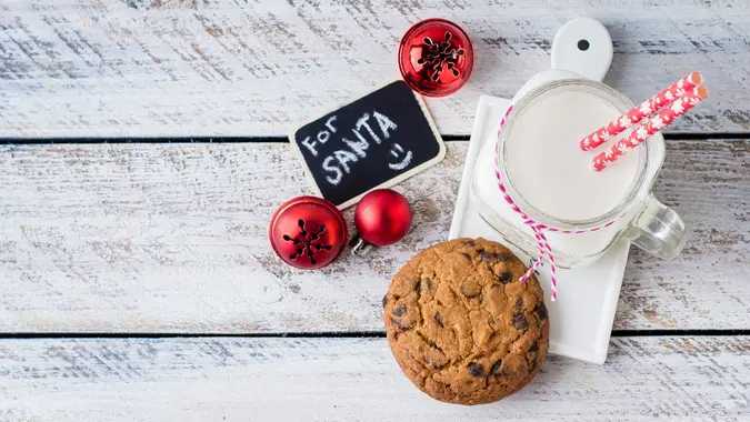 Chocolate chip cookies with a glass of milk on white wooden table background.