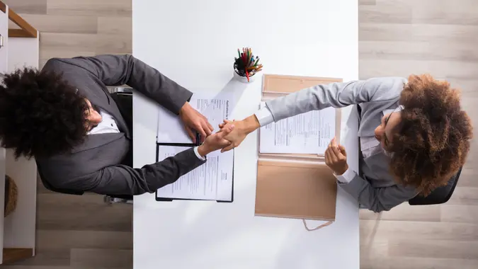 Elevated View Of A Male Manager Shaking Hands With Female Applicant At Workplace.
