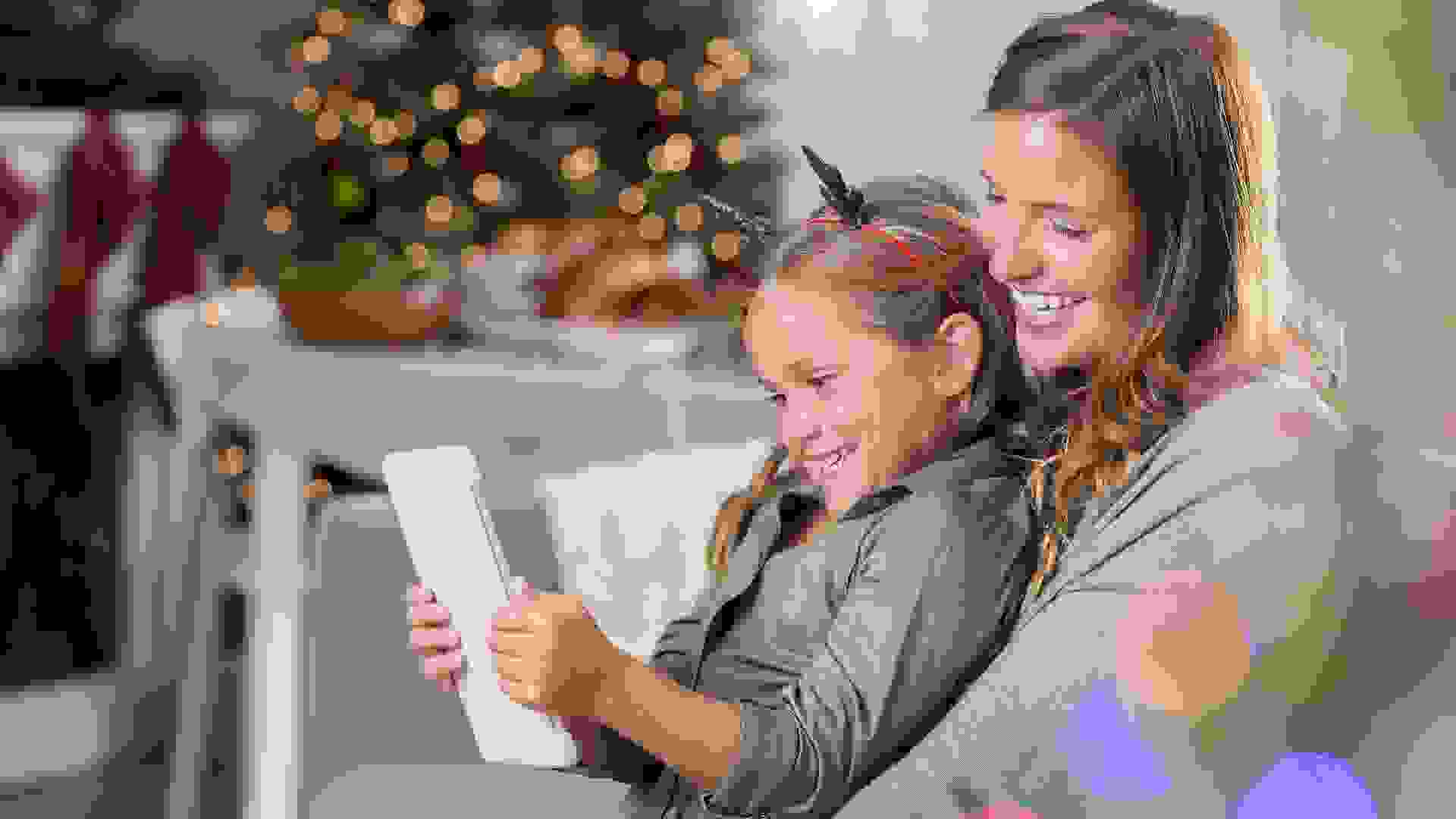 Loving mom and her daughter read an e-reader at Christmastime stock photo