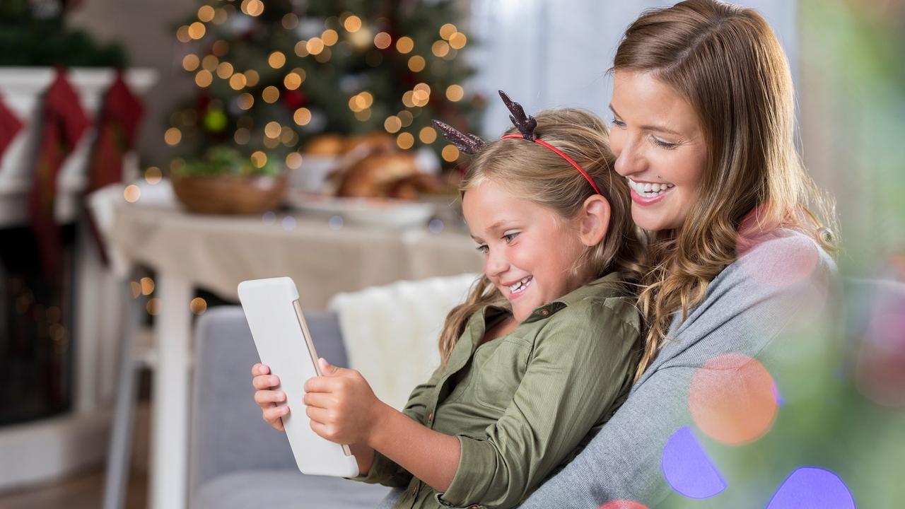 Loving mom and her daughter read an e-reader at Christmastime stock photo