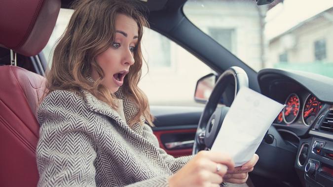 Shocked woman in car reading insurance paper stock photo