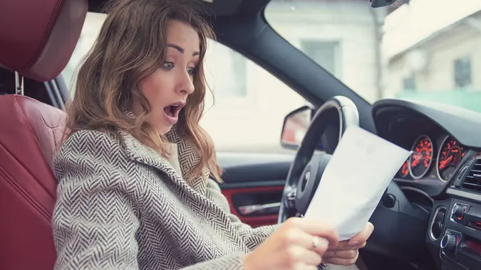 汽车阅读保险纸料的照片震惊了的女人