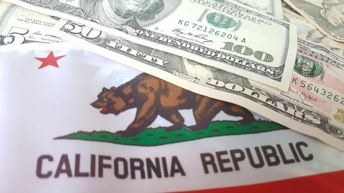 Varying US dollar bills on California flag stock photo