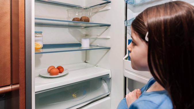 Girl looking at empty fridge due to a crisis stock photo