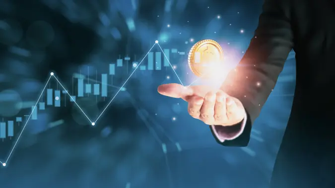 Businessman using hand holding symbol stock graph and chart background,concept growth and development business investment,Stock market and strategy making market plan and stock market fluctuations.