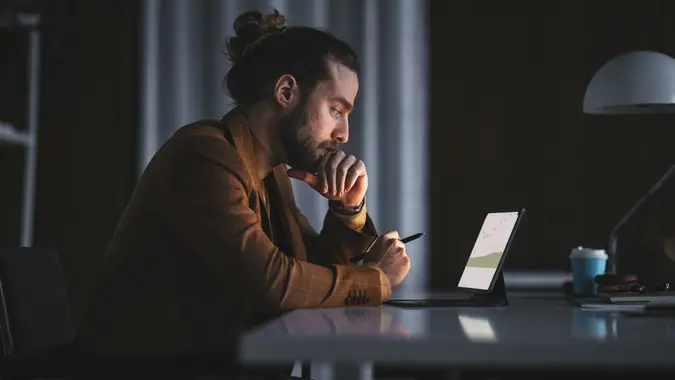 Pensive man working on laptop in office stock photo