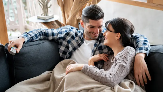 Loving couple watching tv in their winter lodge while lying on the sofa stock photo