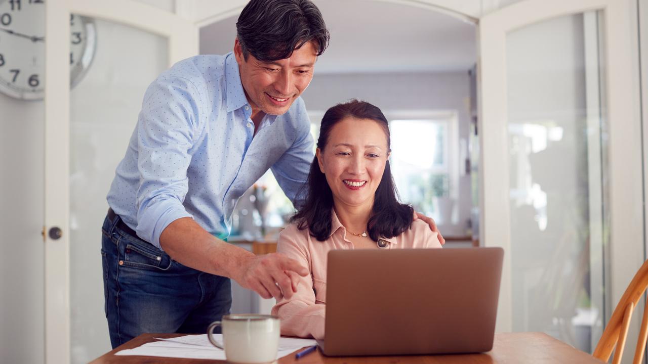 Mature Asian Couple At Home Using Laptop To Organise Household Bills And Finances.