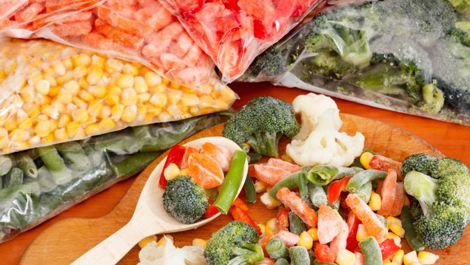 Frozen vegetables on cutting board and plastic bags.
