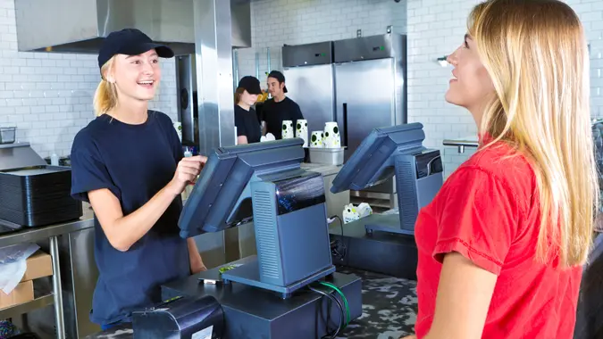 A young woman customer placing her order at a fast food convenience restaurant.