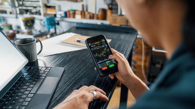 Mid adult man using a smart phone to monitor his cryptocurrency and stock trading stock photo