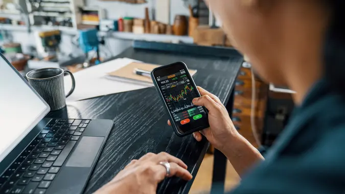 Man using a smart phone to monitor his cryptocurrency and stock trading stock photo