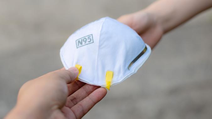 Hand give to / grant / assign / deliver N95 mask or respirator for protect PM 2.5 to other stock photo