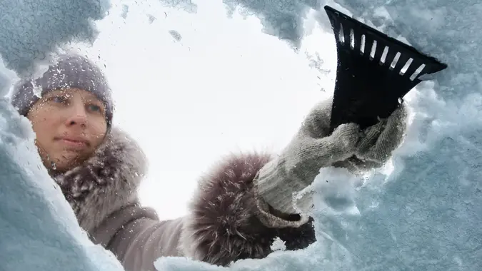 Woman cleaning window of car from the snow with scraper stock photo