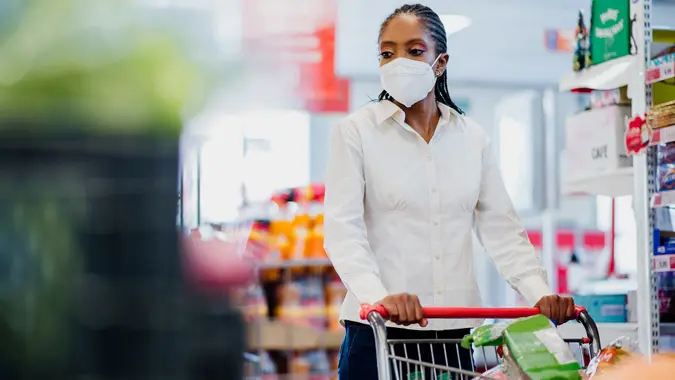 Woman shopping in supermarket wearing coronavirus face mask. stock photo