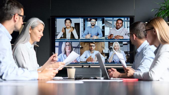Global corporation online videoconference in meeting room with diverse people sitting in modern office and multicultural multiethnic colleagues on big screen monitor. Business technologies concept. stock photo