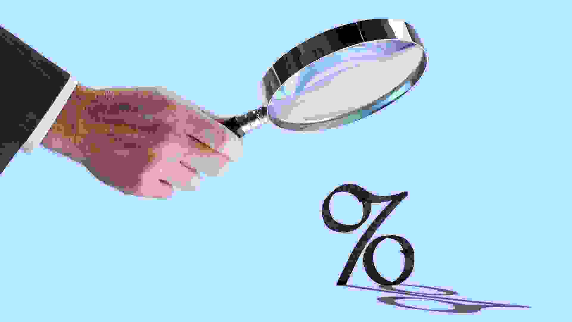 Man Holding Magnifying Glass Looks At Interest Rates stock photo