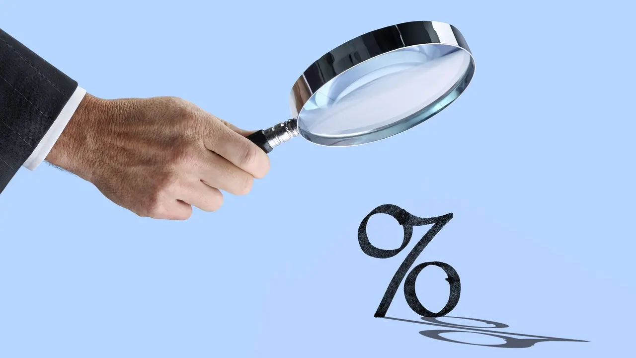 Man Holding Magnifying Glass Looks At Interest Rates stock photo