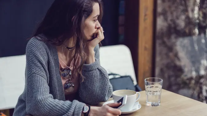 Woman sitting alone, having coffee and texting on her mobile phone stock photo