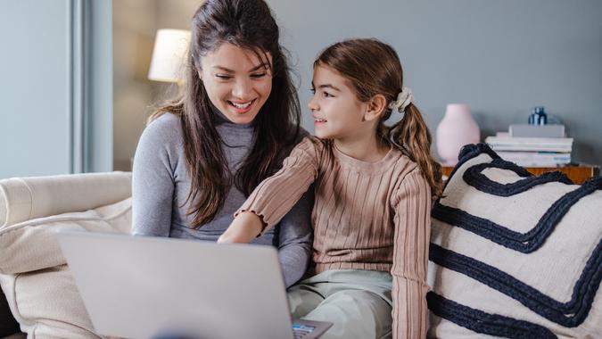 Mother and daughter using laptop at home and smiling stock photo