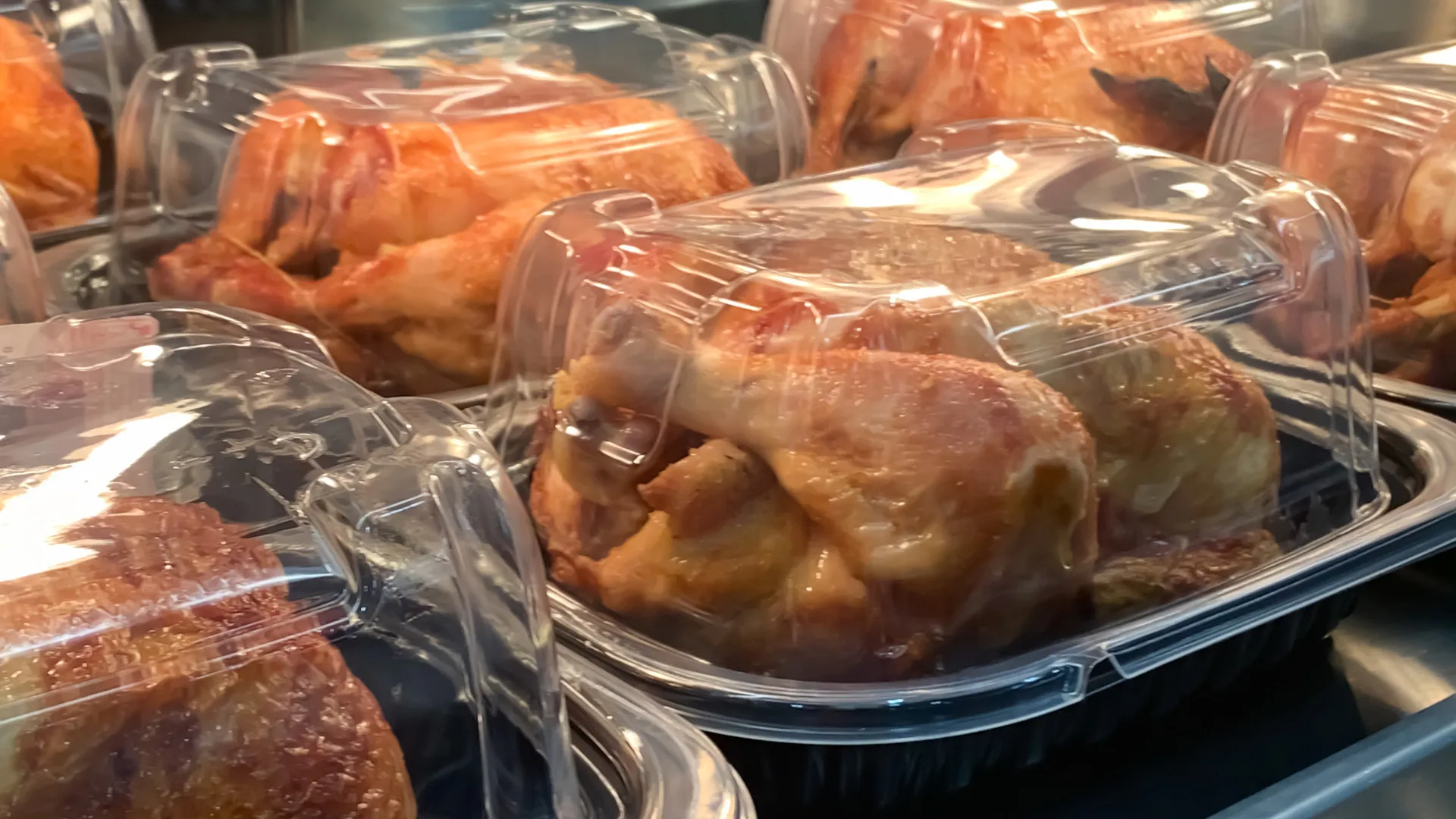 在市场熟食区，包装好的烤鸡放在货架上等待出售。