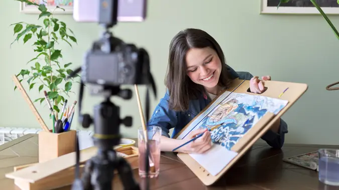 Artist, teenage girl, draws records on video camera for blog.
