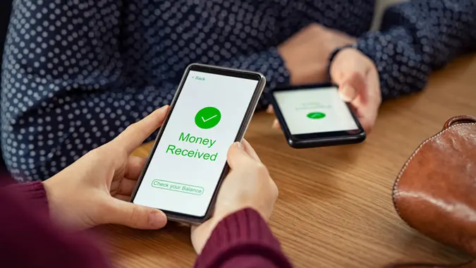 Close up of woman hands holding mobile phone with application to receive money.