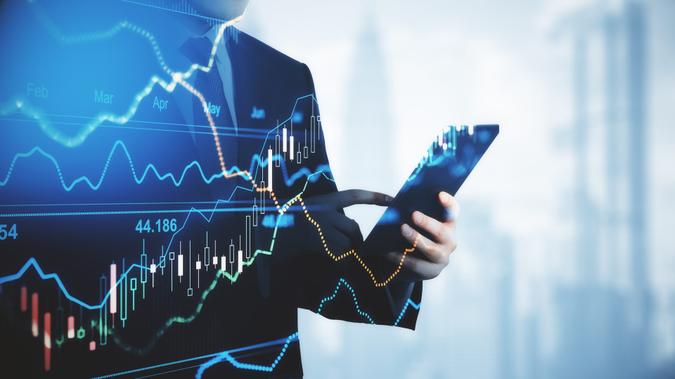 Trading and investment concept trader silhouette with digital tablet and virtual screen with financial chart graphs and candlestick.