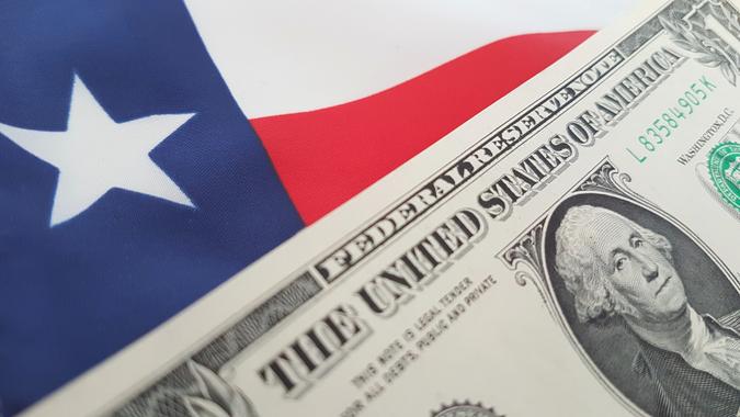 A close up shot of the Texas flag and a new one dollar bill.