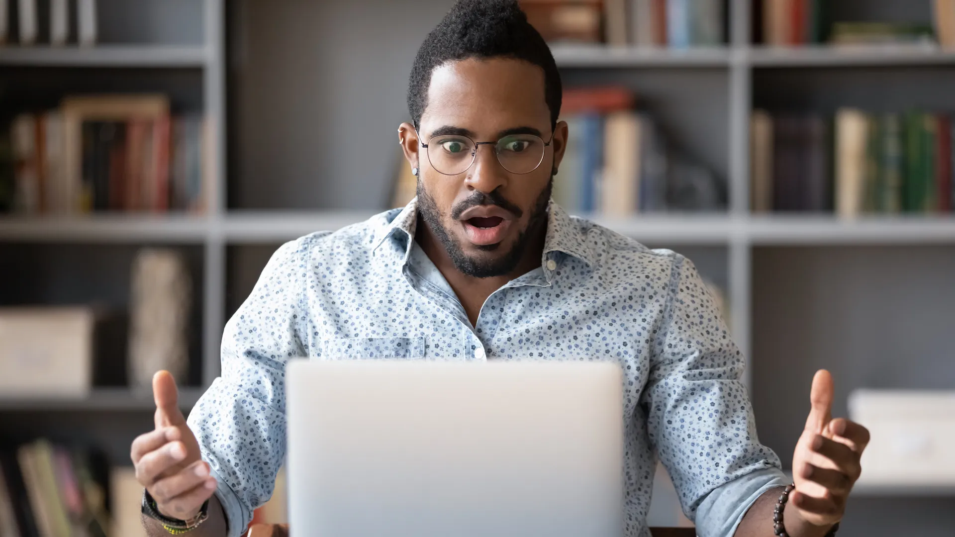Front view shocked millennial african american man in glasses looking at laptop screen, received email with unbelievable news.