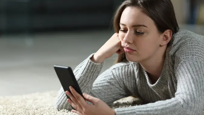 Bored teen checking smart phone at home stock photo