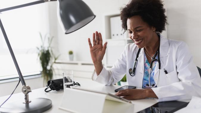 African American woman doctor working at her office doing telemedicine services. Helping patients online and by the phone. Primary care consultations stock photo